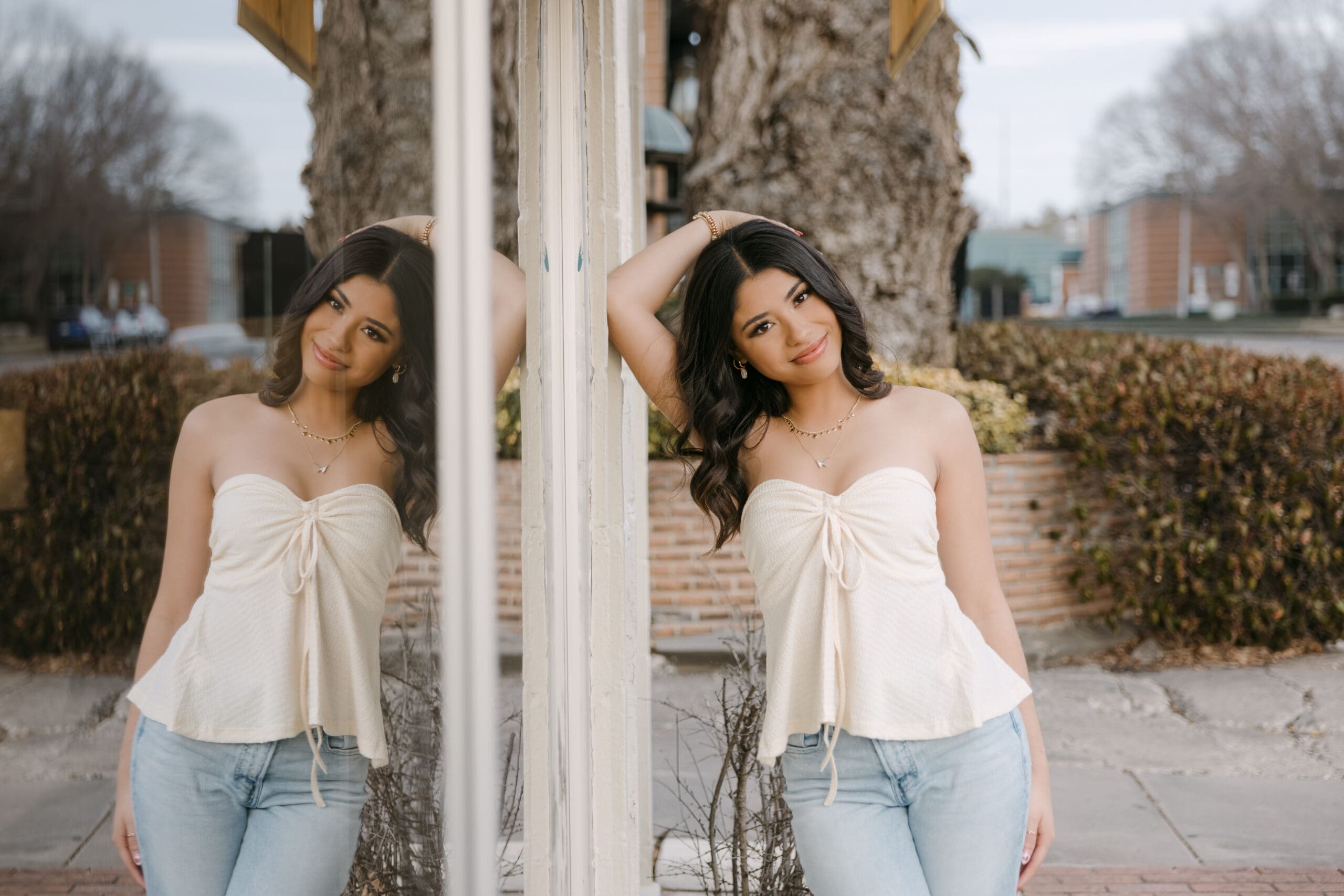 Andale High School Senior leaning on window in Wichita, Kansas in cream strapless top and jeans.